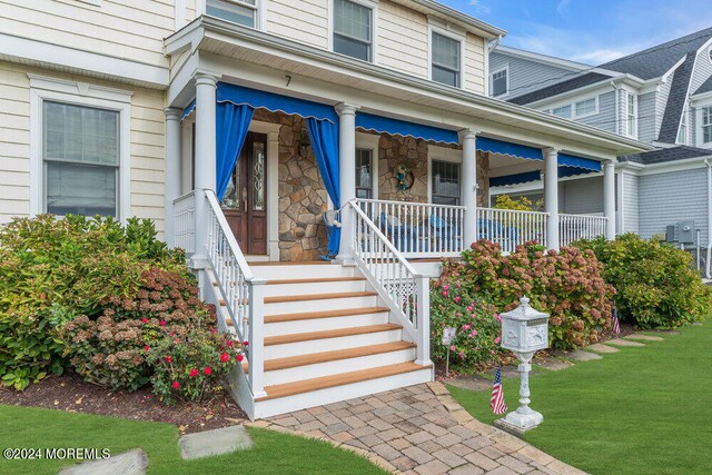 view of exterior entry with a yard and a porch