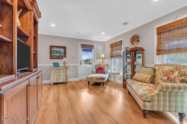 living area with light wood-type flooring and ornamental molding