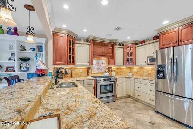 kitchen featuring decorative light fixtures, stainless steel appliances, backsplash, and sink