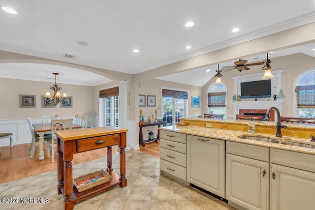 kitchen with light stone counters, plenty of natural light, hanging light fixtures, and sink