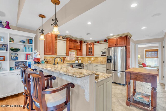 kitchen featuring kitchen peninsula, backsplash, appliances with stainless steel finishes, light stone countertops, and a kitchen bar