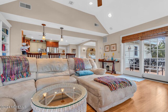 living room featuring high vaulted ceiling, light hardwood / wood-style floors, ceiling fan, and built in features