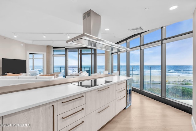 kitchen featuring island exhaust hood, plenty of natural light, a water view, and black electric stovetop