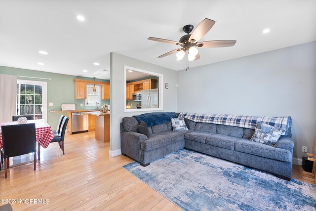 living room with light hardwood / wood-style flooring and ceiling fan