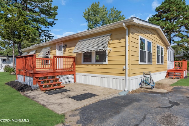 manufactured / mobile home featuring a front lawn and a deck