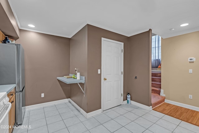 kitchen with stainless steel refrigerator, crown molding, light tile patterned floors, and white stove