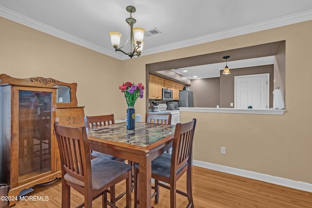 dining room with light hardwood / wood-style floors, ornamental molding, and a chandelier