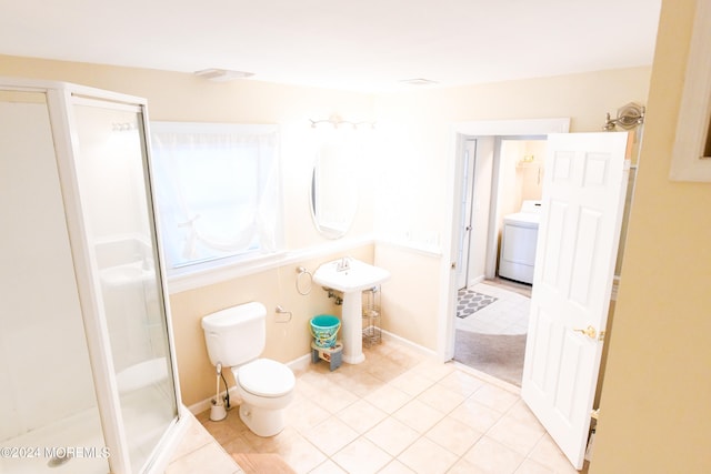 bathroom featuring washer / dryer, sink, tile patterned flooring, a shower with shower door, and toilet