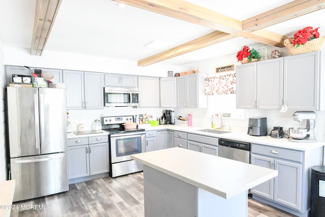 kitchen with beamed ceiling, a kitchen island, light hardwood / wood-style flooring, sink, and stainless steel appliances