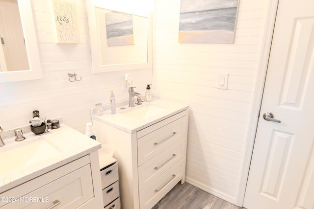 bathroom featuring wood-type flooring, wooden walls, and vanity