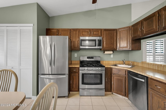 kitchen with sink, lofted ceiling, stainless steel appliances, and light tile patterned floors