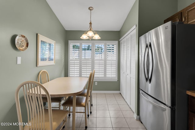 dining area featuring a notable chandelier, lofted ceiling, and light tile patterned floors