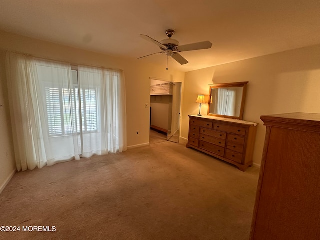 unfurnished bedroom with light carpet, a spacious closet, a closet, and ceiling fan