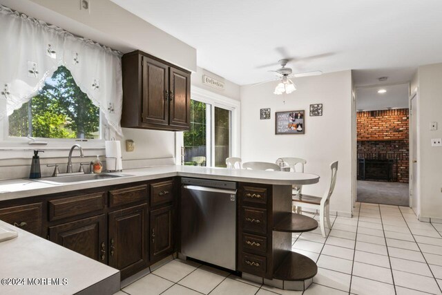 kitchen featuring a brick fireplace, dishwasher, ceiling fan, dark brown cabinetry, and sink