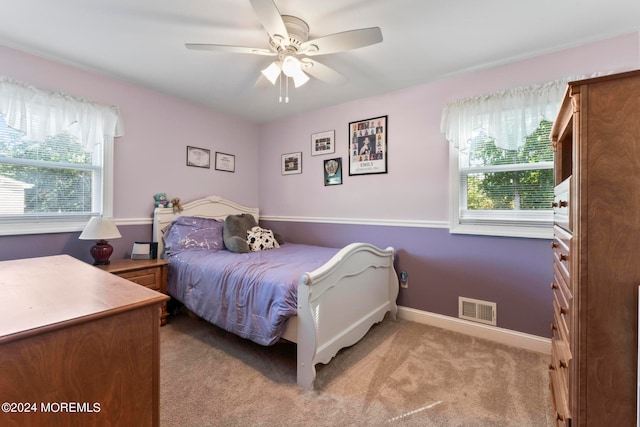 bedroom with light carpet, multiple windows, and ceiling fan