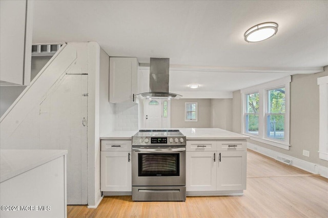 kitchen featuring light wood-type flooring, stainless steel electric stove, range hood, and white cabinetry