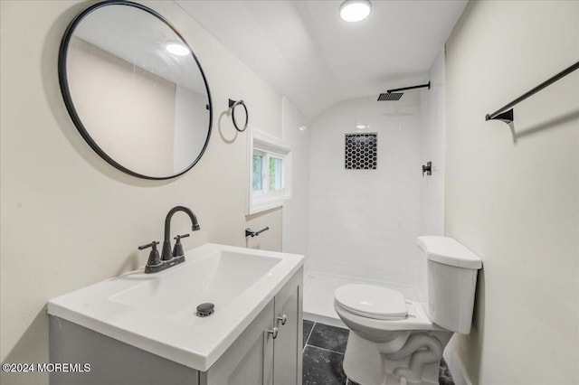 bathroom featuring tile patterned flooring, vaulted ceiling, tiled shower, vanity, and toilet