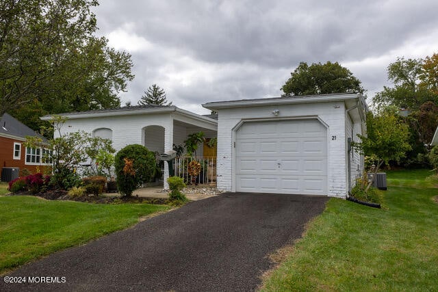 ranch-style home featuring a front yard, a garage, and central AC unit