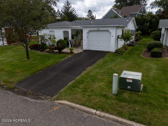 ranch-style house with a garage, central AC unit, and a front yard