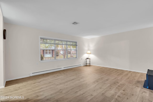 empty room with baseboard heating and light hardwood / wood-style flooring