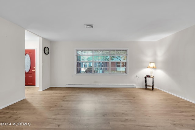 empty room with a baseboard radiator and light hardwood / wood-style flooring