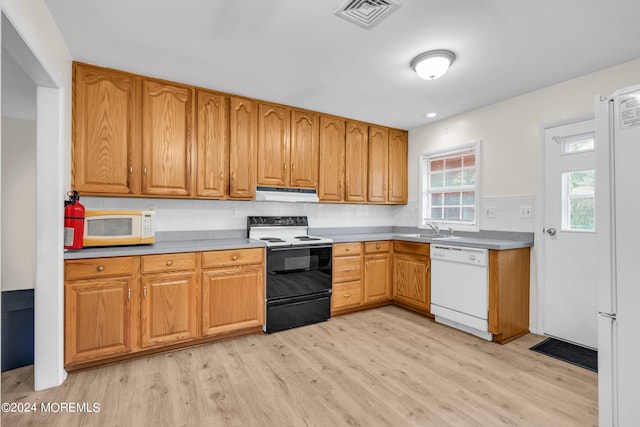 kitchen with light wood-type flooring, sink, white appliances, and tasteful backsplash