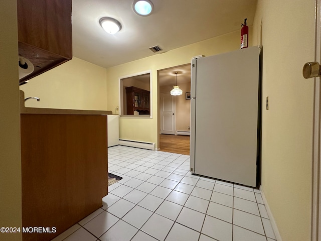 kitchen with pendant lighting, light tile patterned flooring, baseboard heating, and white fridge