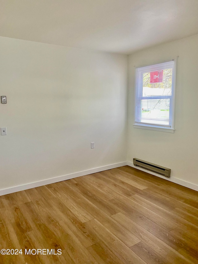 unfurnished room featuring light hardwood / wood-style floors and baseboard heating