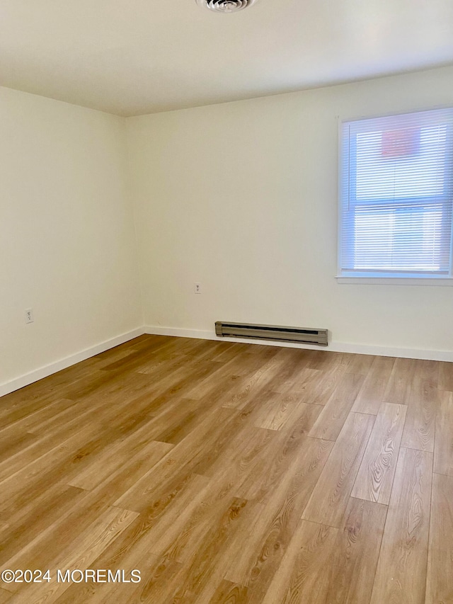 spare room featuring light wood-type flooring and a baseboard radiator