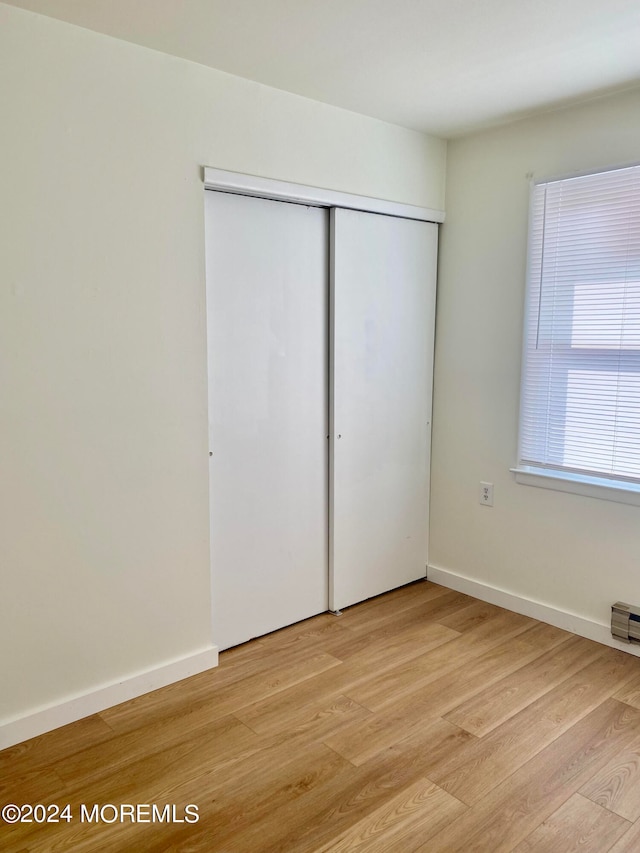 unfurnished bedroom with light hardwood / wood-style flooring and a closet