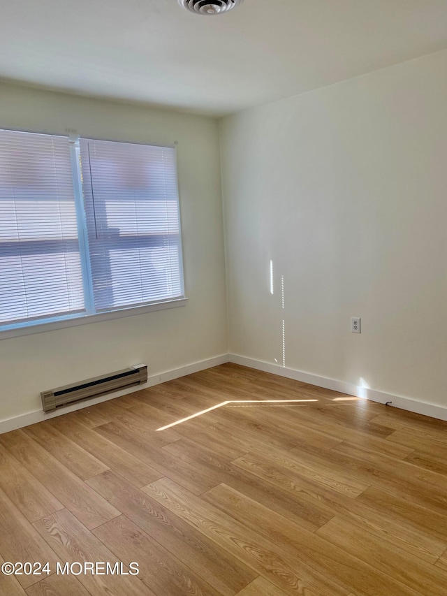 unfurnished room with a baseboard radiator and light wood-type flooring