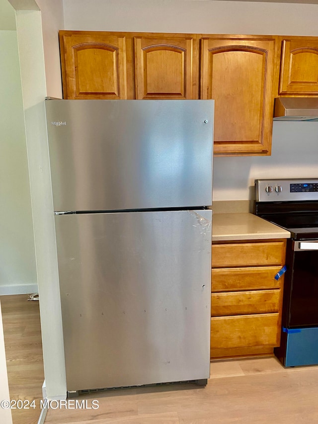 kitchen featuring appliances with stainless steel finishes, light wood-type flooring, and range hood