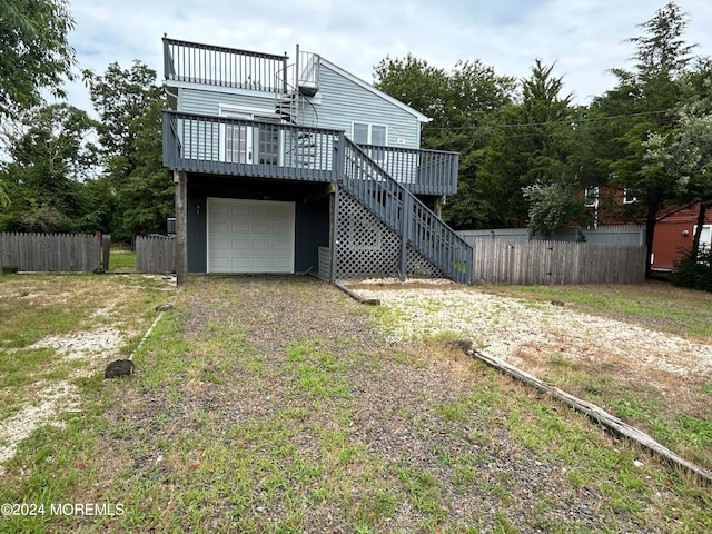 back of house with a garage, a deck, and a yard