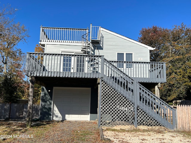 rear view of house with a garage and a wooden deck