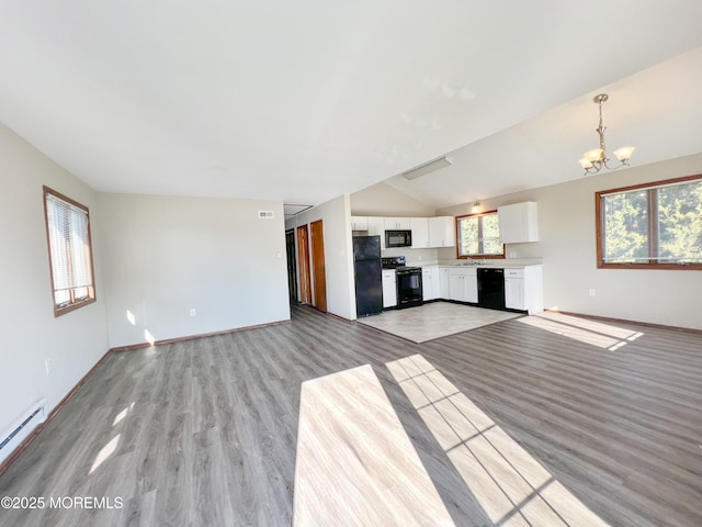 unfurnished living room featuring lofted ceiling, a baseboard heating unit, a sink, a chandelier, and light wood-type flooring