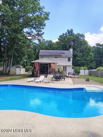 view of pool featuring a patio area and a storage shed