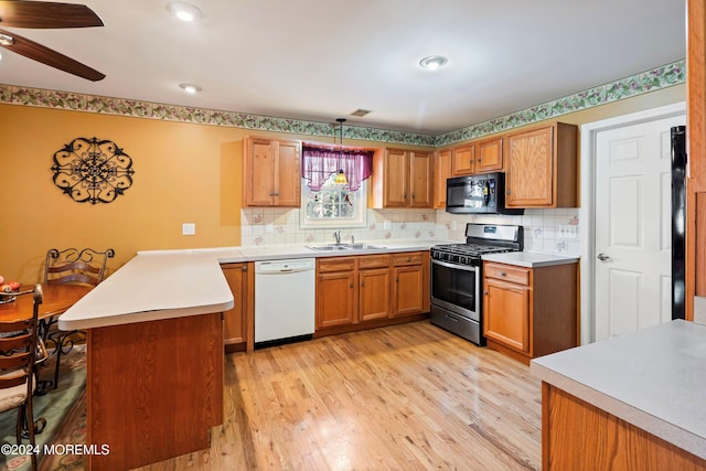 kitchen with light hardwood / wood-style floors, black appliances, hanging light fixtures, and sink