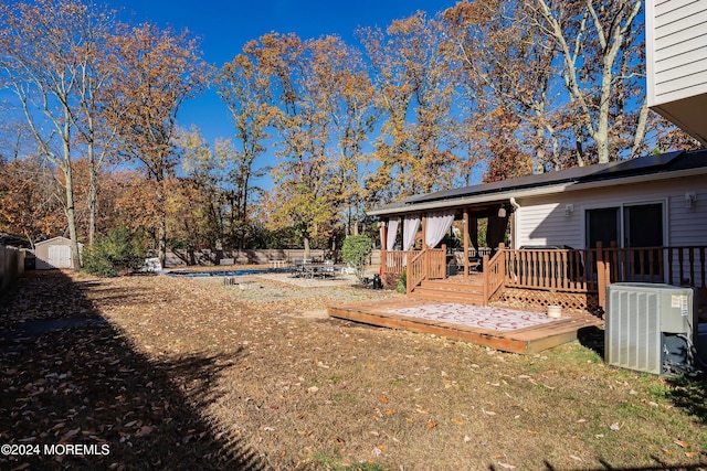 view of yard featuring a storage unit, a deck, and central AC unit