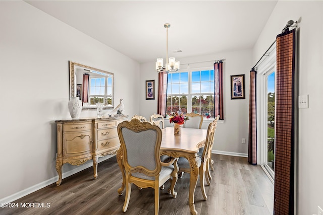 dining area with hardwood / wood-style flooring, a wealth of natural light, and an inviting chandelier