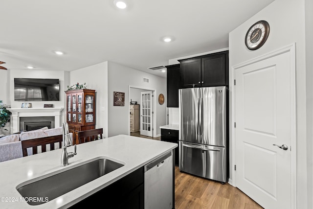 kitchen with stainless steel appliances, sink, and light hardwood / wood-style floors