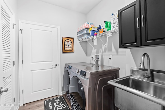 clothes washing area featuring cabinets, wood-type flooring, sink, and independent washer and dryer