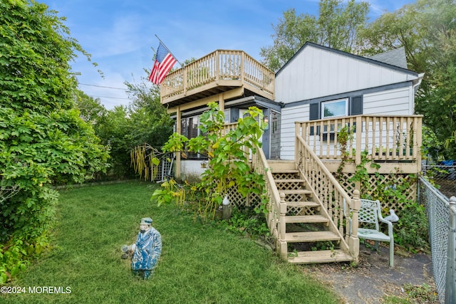 back of property featuring a wooden deck and a yard