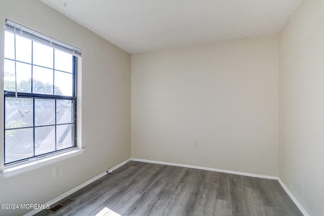 empty room featuring dark hardwood / wood-style floors and a textured ceiling