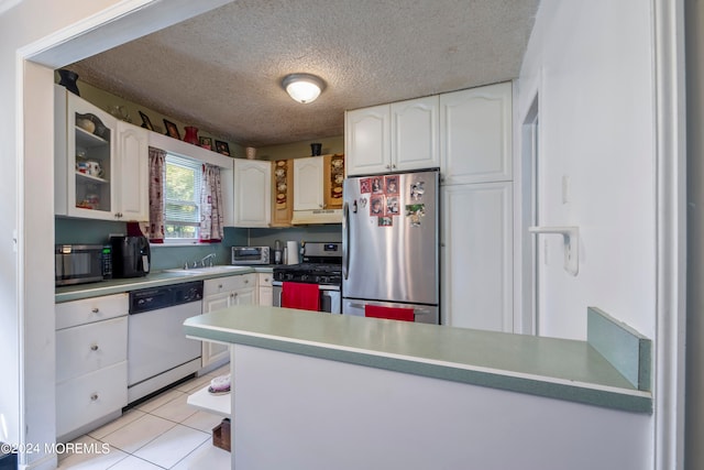 kitchen featuring white cabinetry, sink, stainless steel appliances, light tile patterned floors, and a textured ceiling