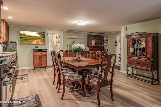 dining space with ornamental molding, a wall unit AC, light wood-style flooring, and baseboards