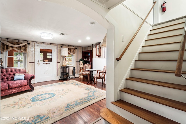 living room with a baseboard radiator, visible vents, stairway, and wood finished floors