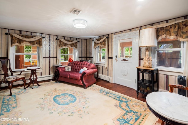 living area featuring visible vents, baseboard heating, and wood finished floors