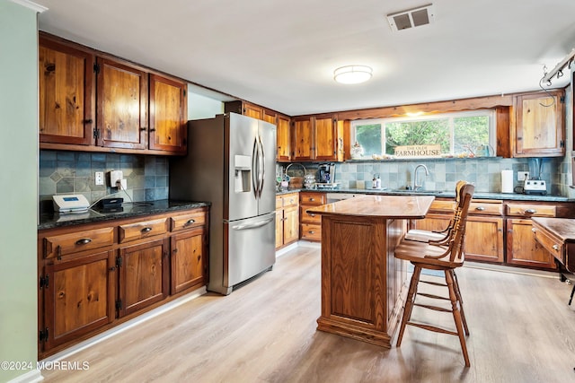 kitchen featuring light wood finished floors, brown cabinetry, and stainless steel refrigerator with ice dispenser