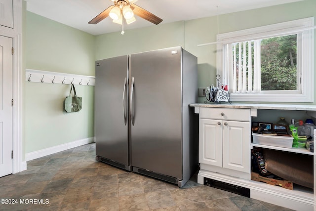 kitchen featuring light countertops, a ceiling fan, freestanding refrigerator, white cabinets, and baseboards