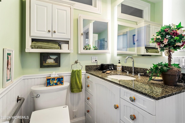 bathroom featuring toilet, wainscoting, and vanity